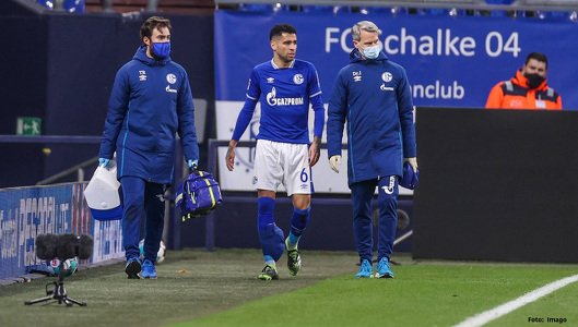 Zwei Mannschaftsärzte mit einem verletzten Spieler des FC Schalke 04 am Spielfeldrand.